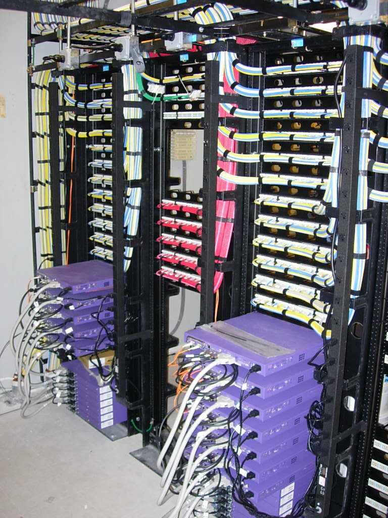 Network cabling rack with color-coded cable bundles dressed and routed vertically through cable management