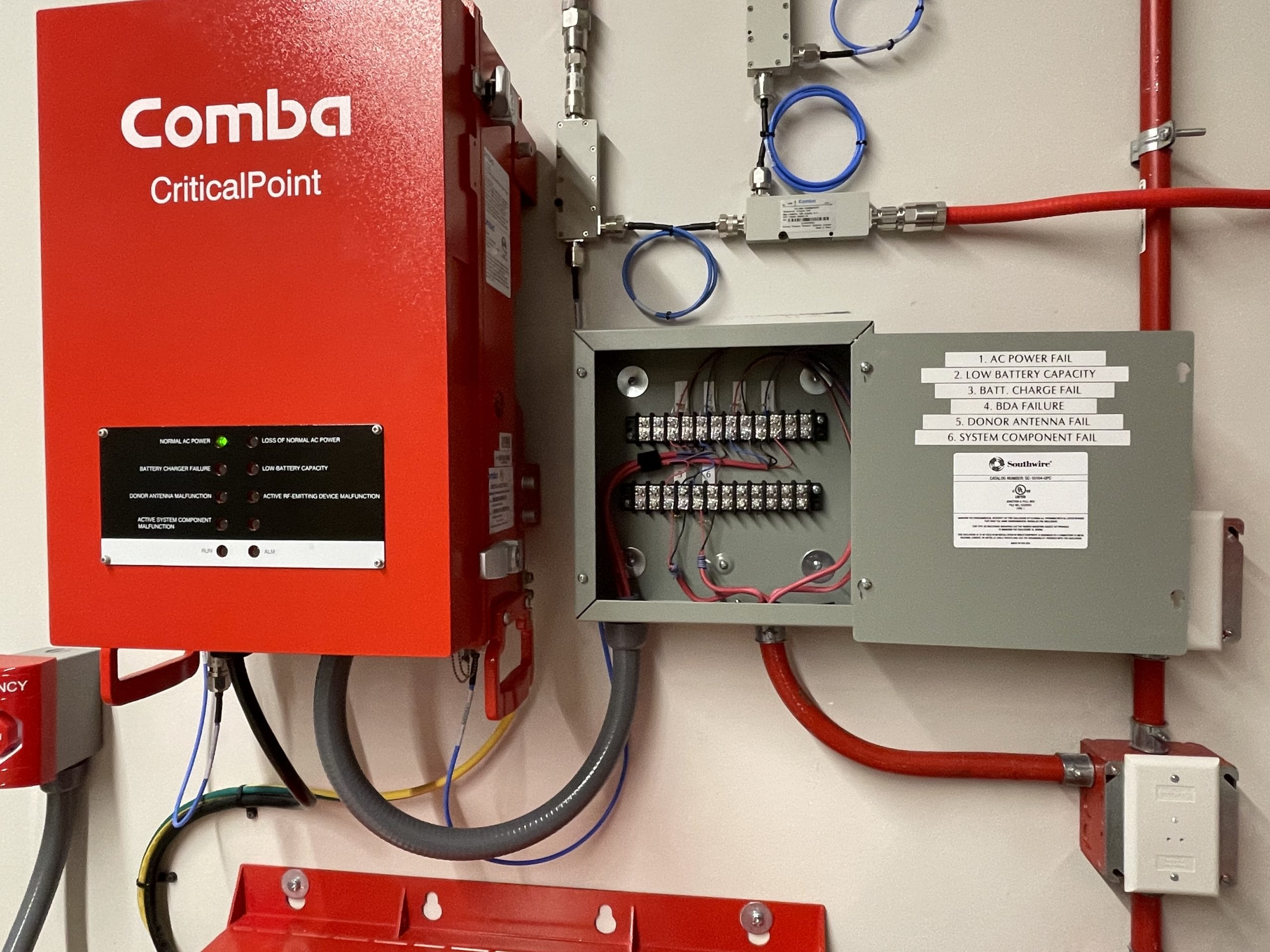 Emergency responder radio communication system head-end equipment mounted in a building electrical room, with red enclosures and conduit